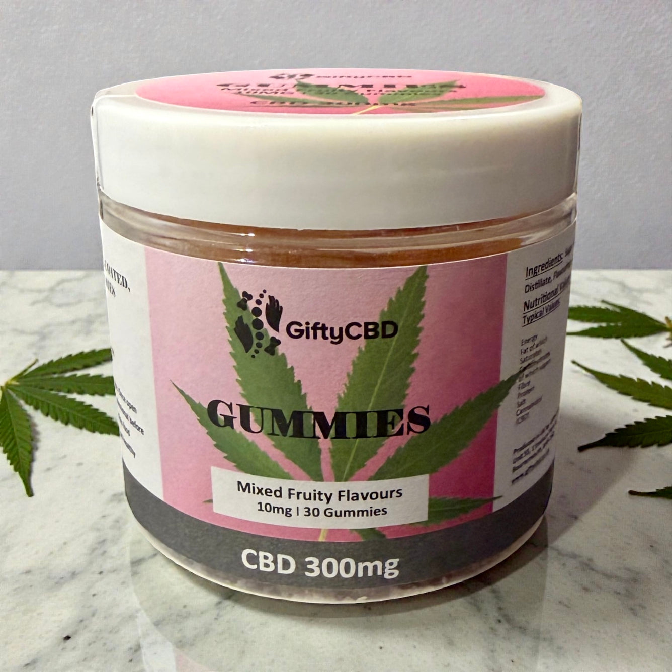 Jar of GiftyCBD gummies with pink label on a marble surface