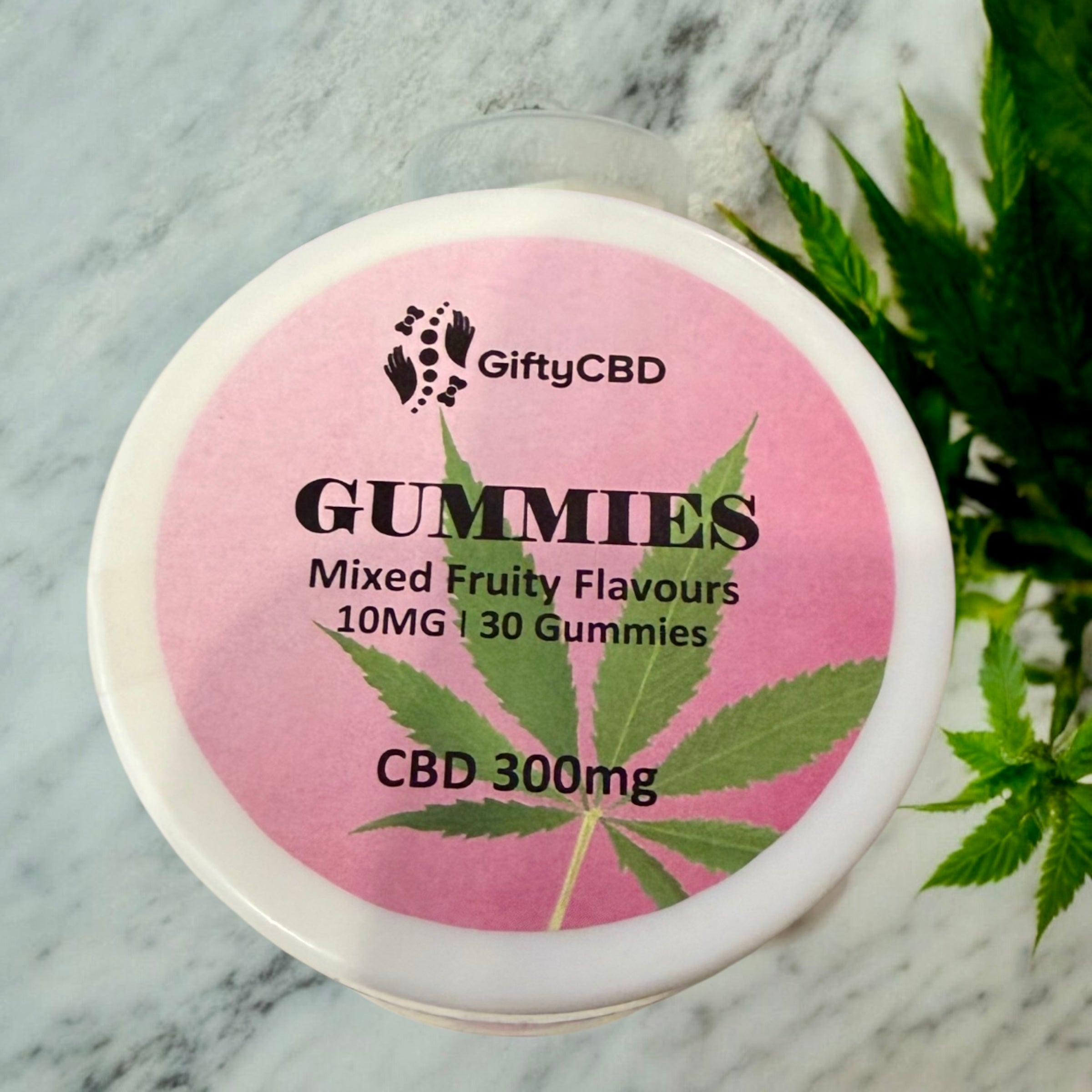 Gummy jar with GiftyCBD branding on a marble surface with cannabis leaves.